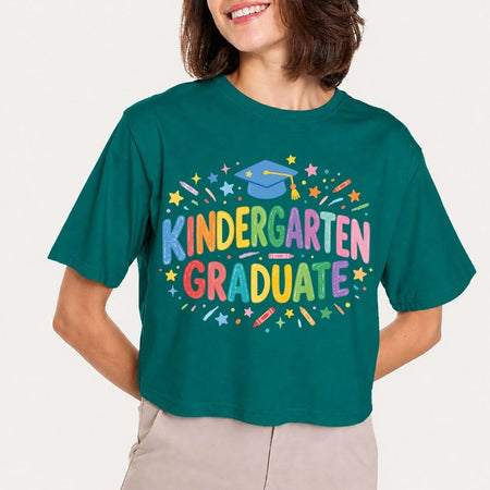 Person wearing a teal t-shirt with 'Kindergarten Graduate' text and graphics on a plain background