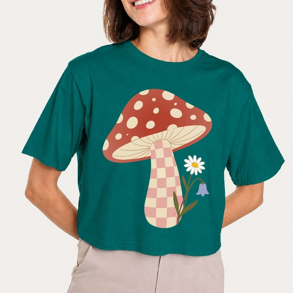 Person wearing a teal t-shirt with a mushroom graphic design.