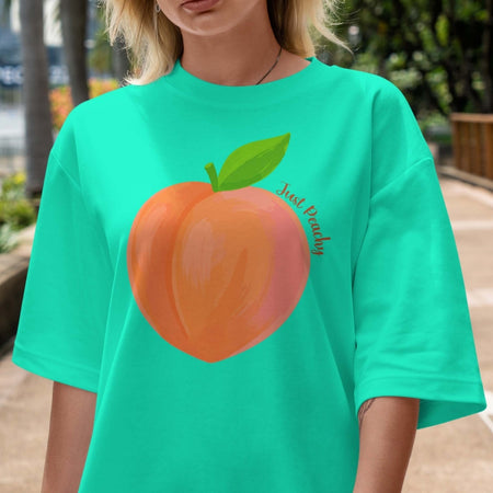 Person wearing a teal t-shirt with a peach graphic and 'Just Peachy' text.