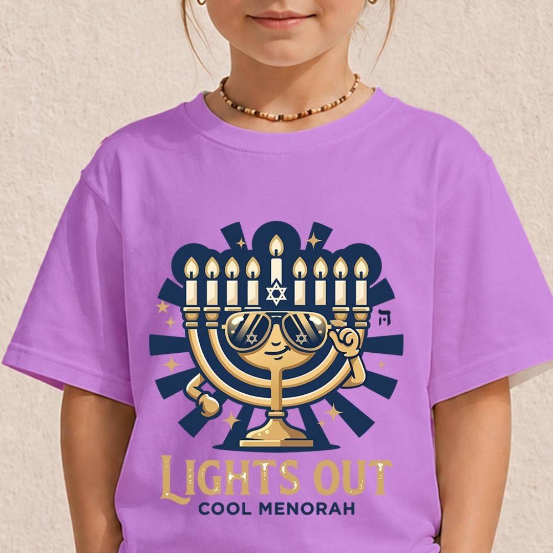 A child wearing a light purple t-shirt featuring a fun graphic of a golden Hanukkah menorah wearing sunglasses above the text "LIGHTS OUT COOL MENORAH".