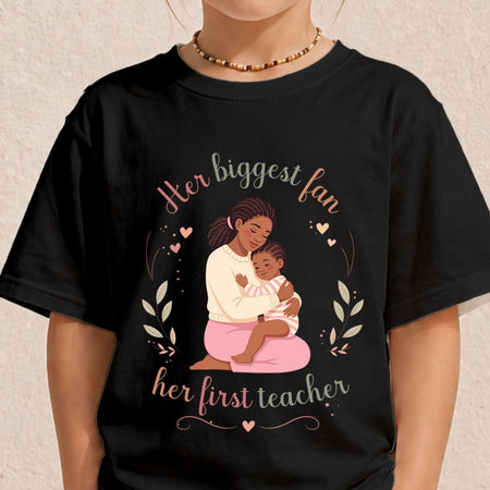 Close-up of a child wearing a black crewneck t-shirt with a sweet illustration of a mother and daughter surrounded by hearts and the text Her biggest fan, her first teacher.