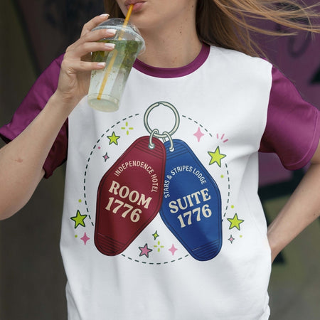 Person wearing a t-shirt with motel keychain design and holding a drink.