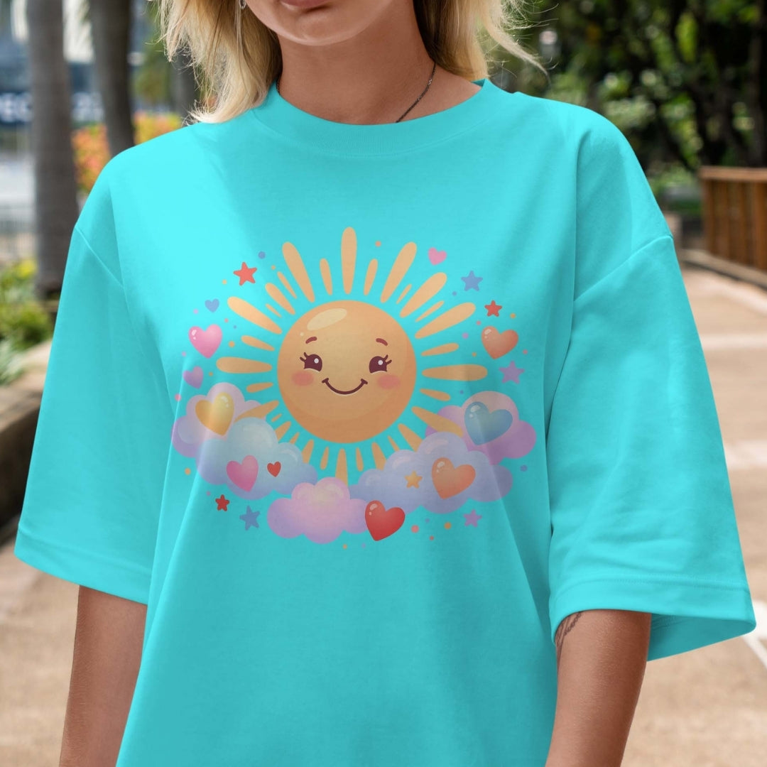 Person wearing a turquoise t-shirt with a sun and heart design outdoors.