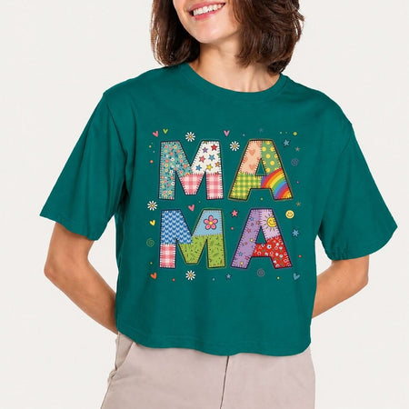 Person wearing a teal t-shirt with colorful 'MAMA' text design on a plain background