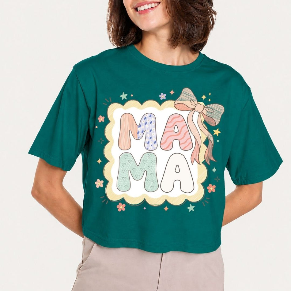 Person wearing a teal t-shirt with 'MAMA' graphic design on a plain background