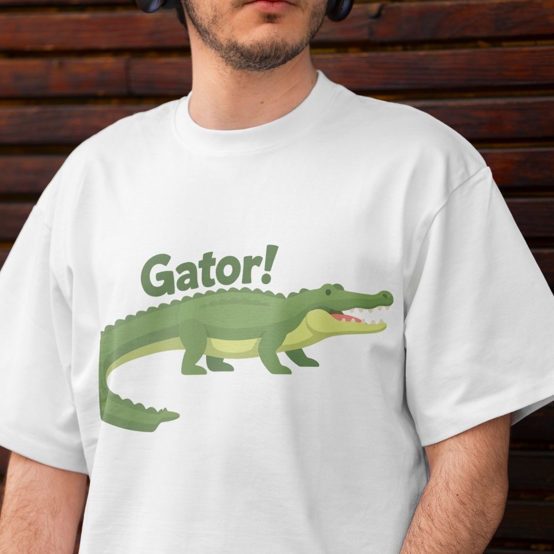 Close-up of a man wearing a white oversized crewneck t-shirt printed with a playful green alligator graphic and the word "Gator!".