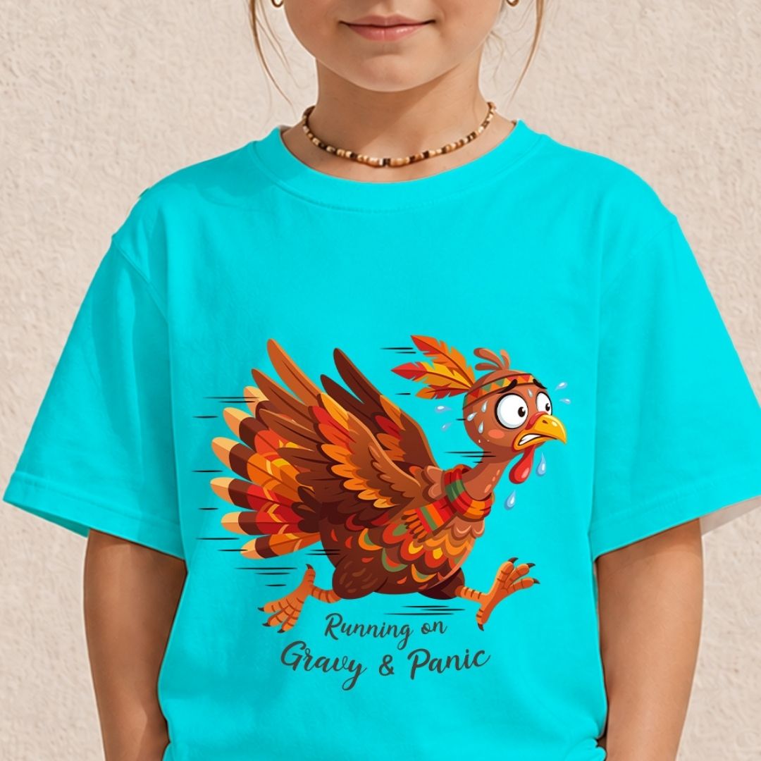 A child wearing a bright turquoise graphic T-shirt with a cartoon turkey in brown, orange, and red tones, plus the text 'Running on Gravy & Panic' on the front, against a light textured wall.