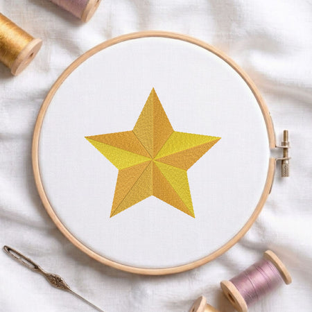 Golden 3D star machine embroidery design displayed in a wooden hoop on white fabric with thread spools and a needle   