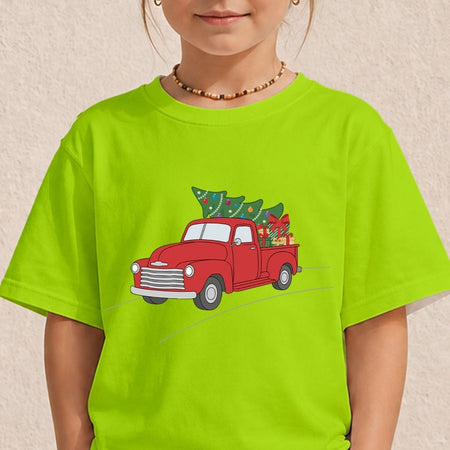 A child wearing a bright lime green t-shirt with a graphic of a red vintage truck carrying a green Christmas tree. The child is also wearing a beaded necklace against a textured beige wall.