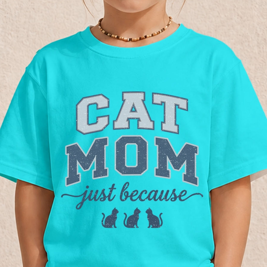 Close-up of a youth or toddler wearing a bright cyan blue t-shirt printed with a vintage varsity-style "Cat Mom just because" design.