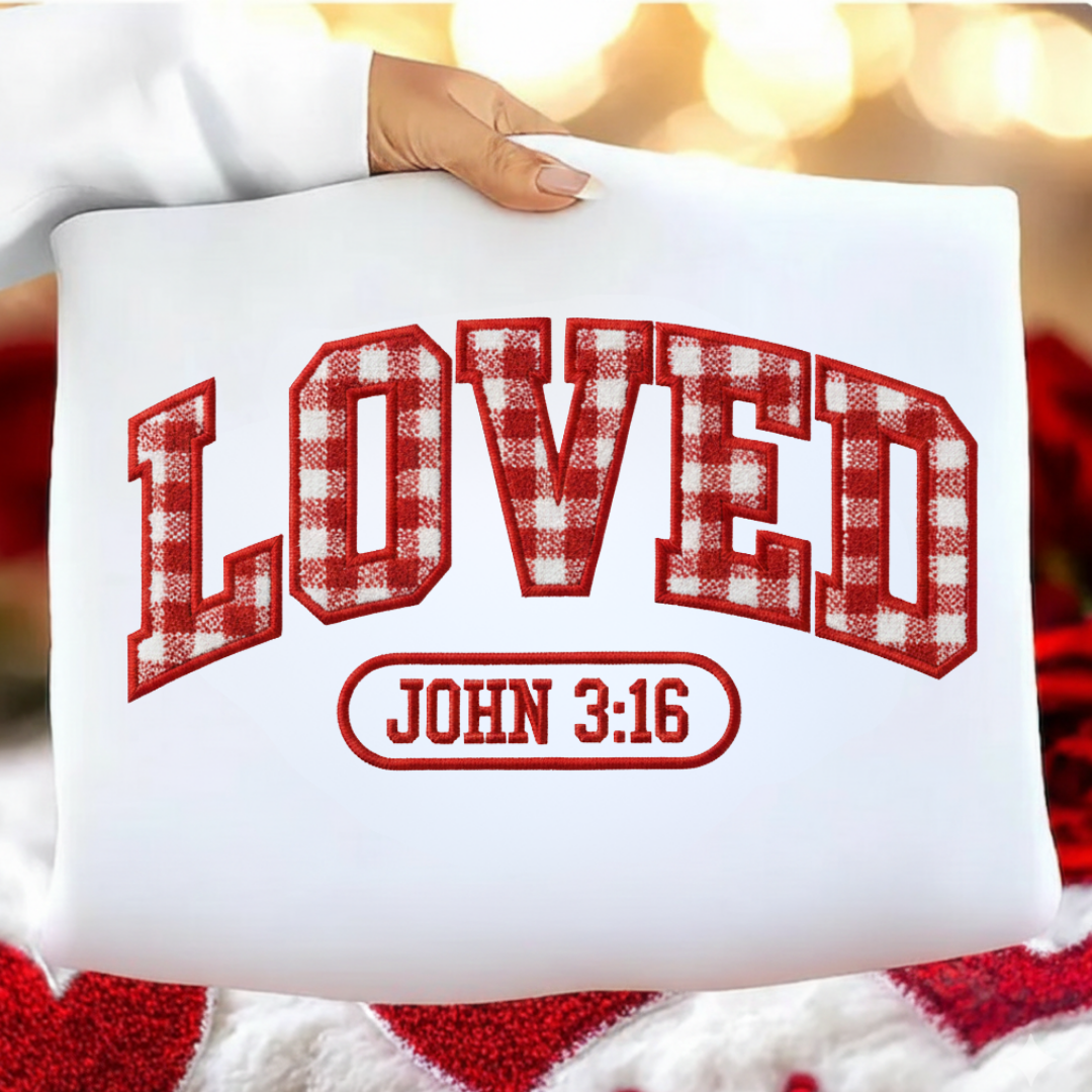 White pillow with red plaid text 'LOVED' and 'JOHN 3:16' held by a person against a blurred background.