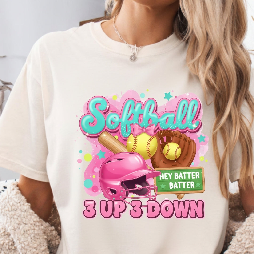White t-shirt with colorful softball-themed design featuring a helmet, bat, and balls.