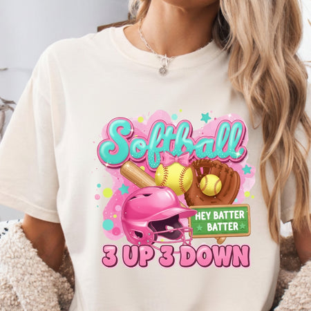 White t-shirt with colorful softball-themed design featuring a helmet, bat, and balls.
