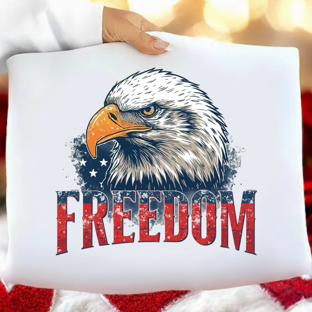 White pillow with an eagle design and 'FREEDOM' text on a blurred American flag background