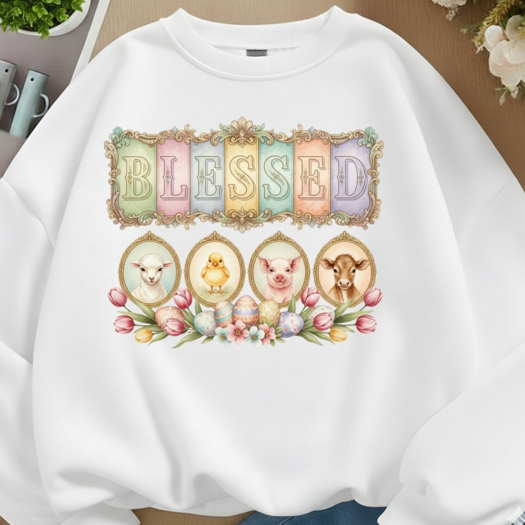 White sweatshirt with 'BLESSED' design featuring animals and flowers on a neutral background.