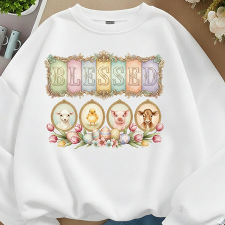 White sweatshirt with 'BLESSED' design featuring animals and flowers on a neutral background.