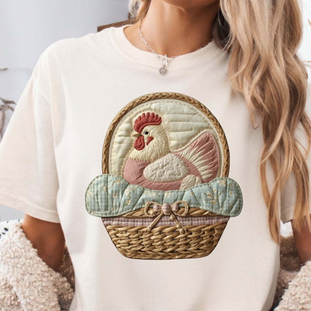 White t-shirt with a decorative rooster design on a neutral background