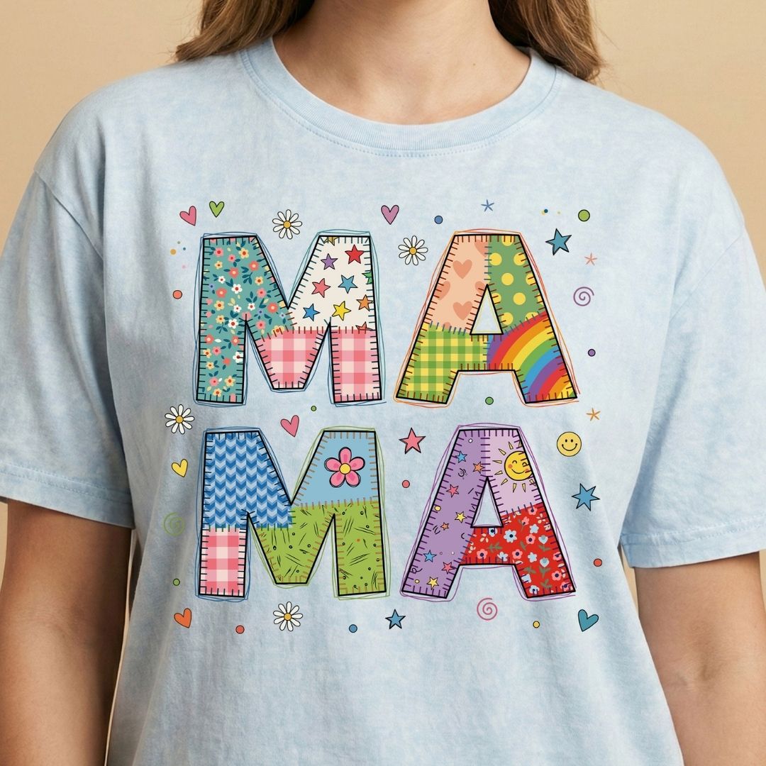 Light blue t-shirt with colorful 'MAMA' text design on a beige background