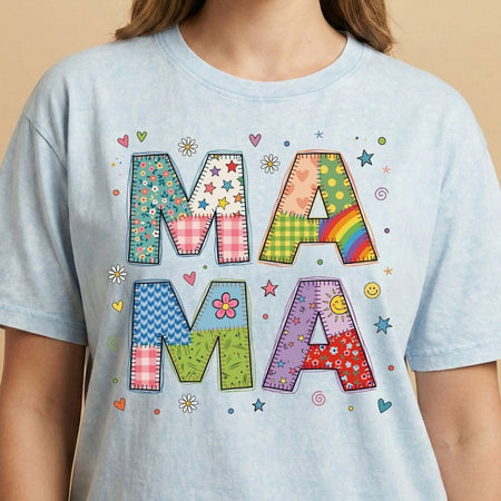 Light blue t-shirt with colorful 'MAMA' text design on a beige background