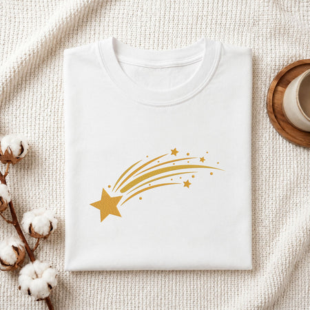 Folded white cotton t-shirt mockup featuring a golden shooting star machine embroidery design, styled with cotton stems and a wooden cup
