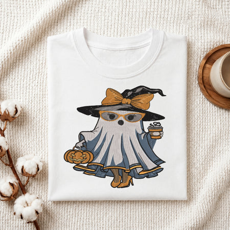 Folded white t-shirt mockup with an embroidered fashionable ghost wearing a witch hat, glasses, and high heels while holding coffee and a pumpkin.