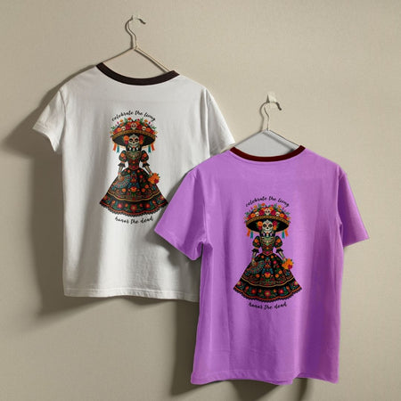 Two short-sleeve ringer T-shirts hanging on hangers against a plain beige wall. The left shirt is white with a dark brown collar and features a colorful Day of the Dead sugar skull graphic on the back.