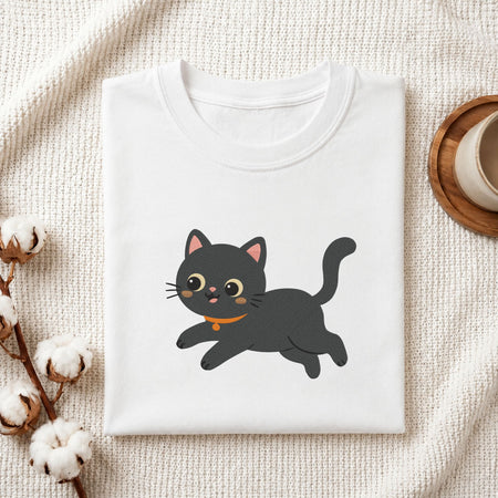 Folded white cotton t-shirt mockup featuring a cute playful black cat machine embroidery design, styled with cotton stems and a wooden cup