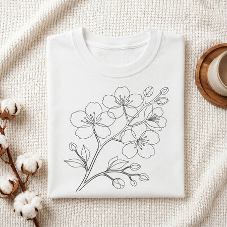 A minimalist single line art cherry blossom flower branch embroidery design stitched on the front of a folded white cotton t-shirt.