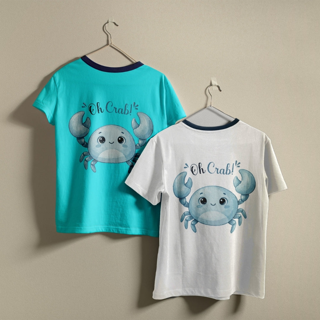 Two t-shirts hanging on hangers, one turquoise and one white, both printed with a blue cartoon crab graphic and the text "Oh Crab!"