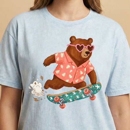 Light blue t-shirt with a bear graphic wearing sunglasses and a hawaiian shirt on a beige background