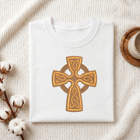 Folded white cotton t-shirt featuring an embroidered golden Celtic cross design centered on the chest.