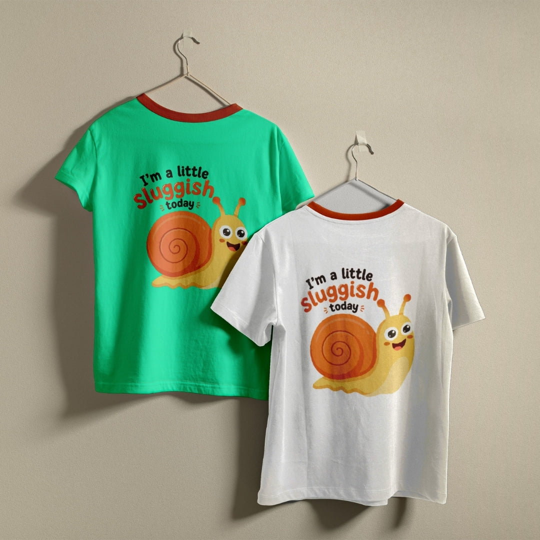 Two t-shirts hanging on hangers, one green and one white, both printed with a cute, smiling cartoon snail graphic and the text "I’m a little sluggish today."