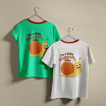 Two t-shirts hanging on hangers, one green and one white, both printed with a cute, smiling cartoon snail graphic and the text "I’m a little sluggish today."