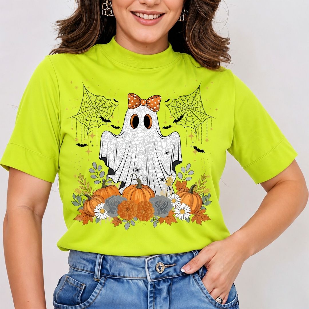 A woman wearing a bright lime green mock-neck t-shirt with a Halloween graphic of a ghost, pumpkins, spiders, and bats, paired with blue jeans.