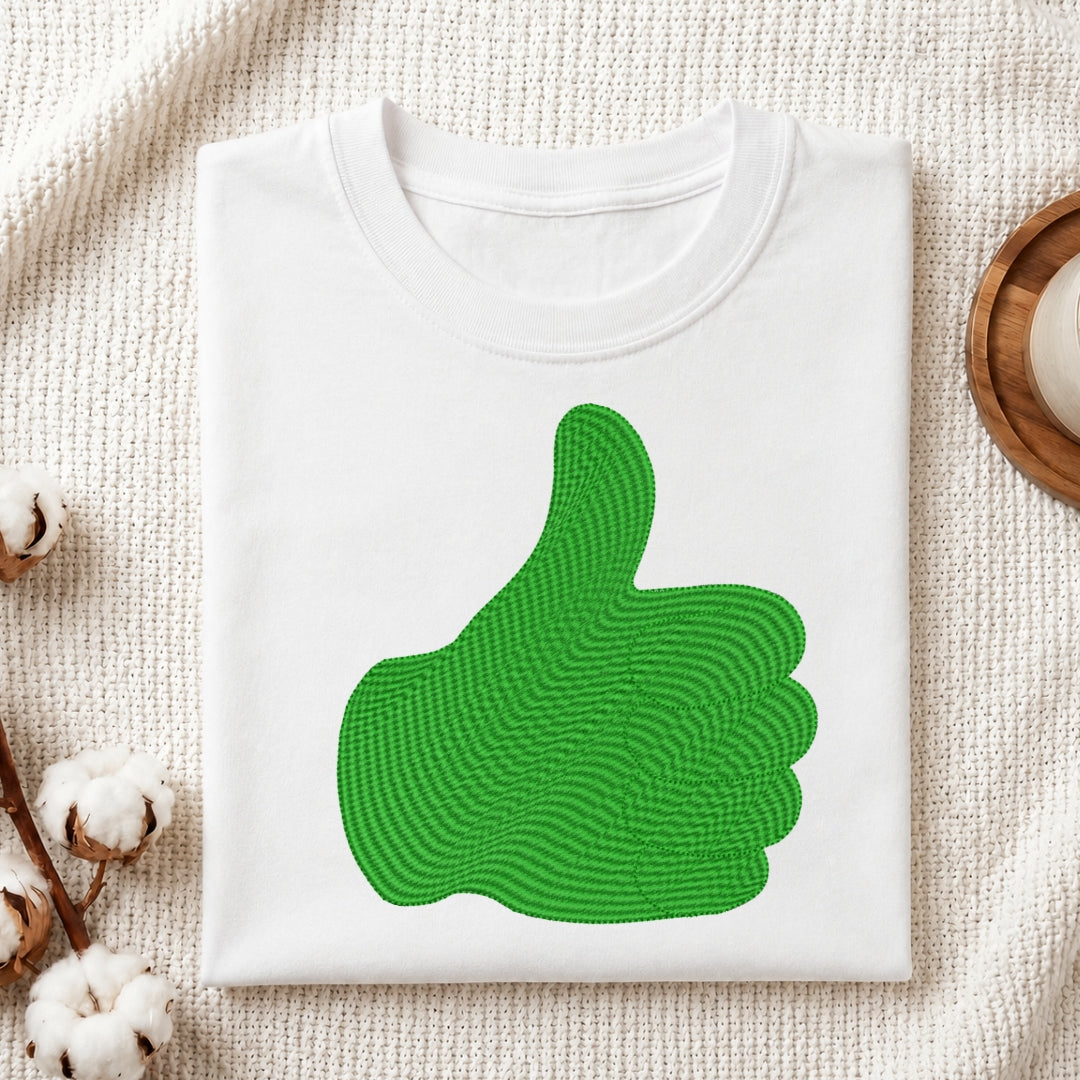 White sweatshirt with a green thumbs-up design on a textured surface.