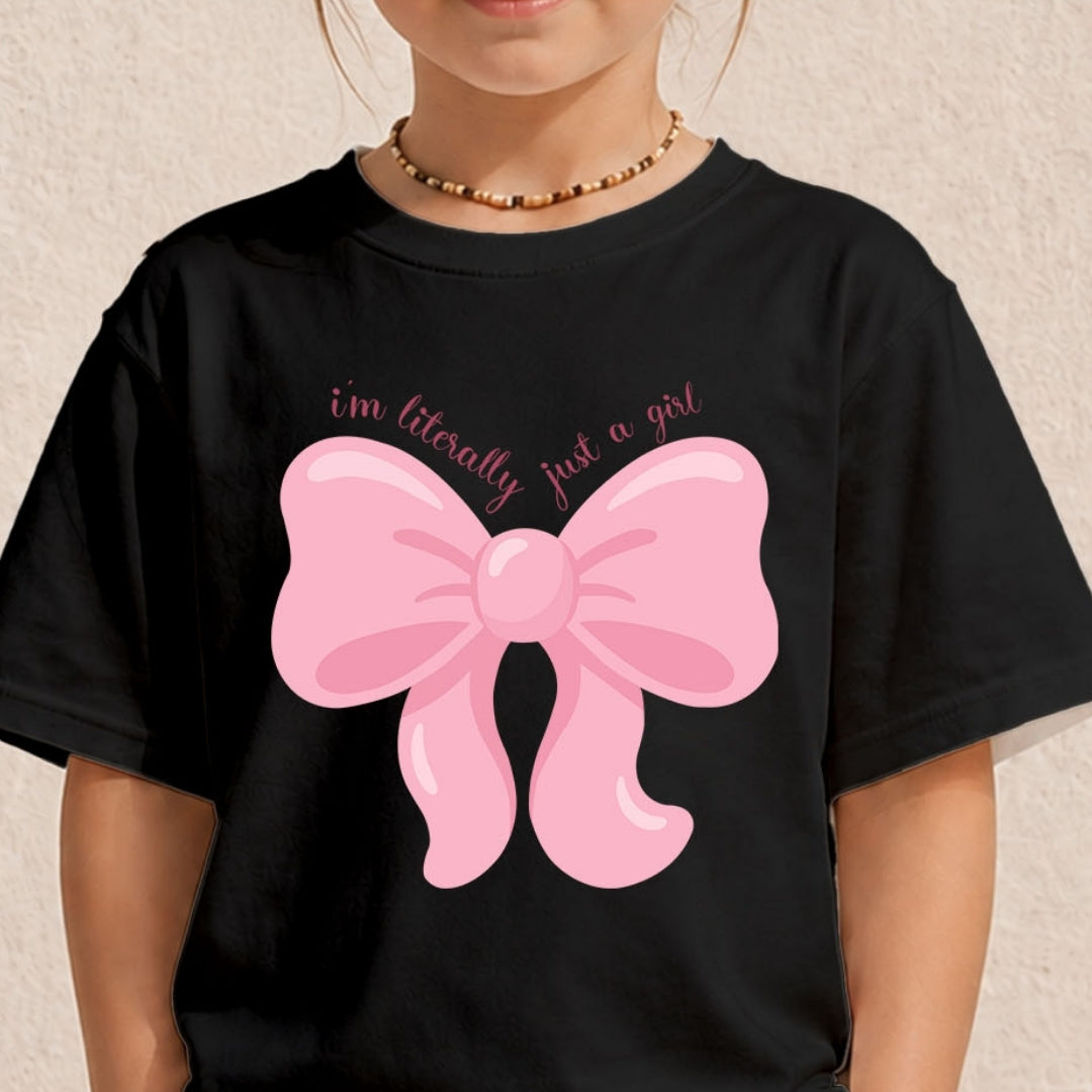 Child wearing a black t-shirt printed with the pink coquette bow graphic and text.