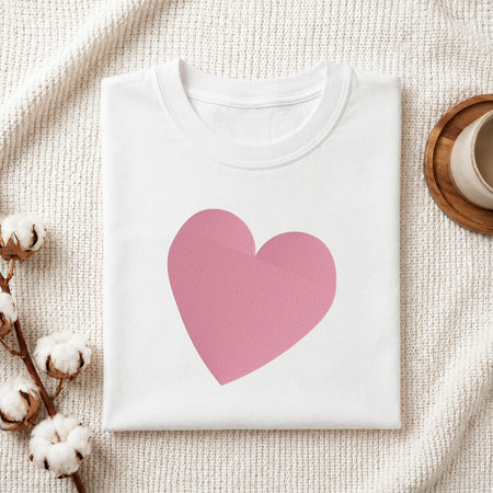 Folded white cotton t-shirt mockup featuring a minimalist heart machine embroidery design, styled with cotton stems and a wooden cup   