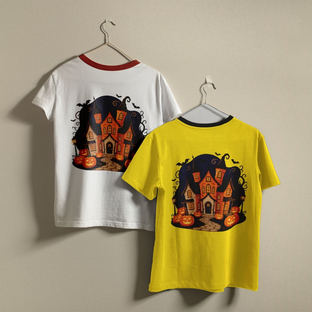 Two ringer t-shirts with a spooky haunted house graphic on the front and back, hanging on hangers against a plain beige wall. One shirt is white with a red collar, and the other is yellow with a black collar.