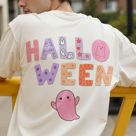 A person shown from behind wearing a cream-colored t-shirt with a colorful 'HALLOWEEN' graphic and a pink ghost on the back, sitting on a yellow bench.