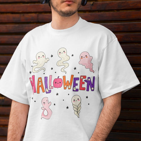 A man wearing a white crewneck t-shirt with a colorful cartoon Halloween graphic featuring cute ghosts and the word 'HALLOWEEN' in stylized letters, set against a dark wooden plank background.