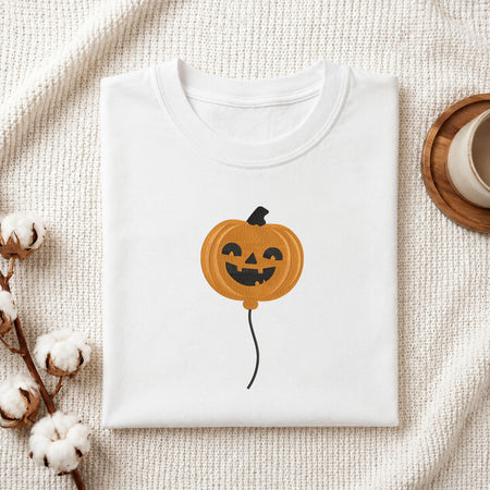  Folded white cotton t-shirt mockup featuring a cute ghost machine embroidery design, styled with cotton stems and a wooden cup   