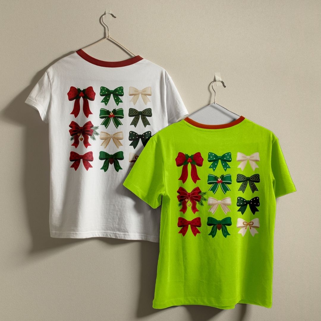 Two children's short-sleeve T-shirts hanging on hangers against a plain beige wall. The left shirt is white with a red collar and the back shows multiple bow graphics in red, green, and beige.