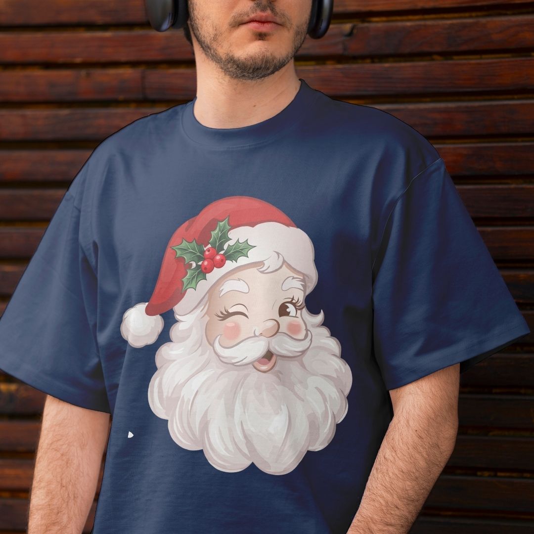 A man wearing a navy blue t-shirt with a large graphic of a winking Santa Claus face wearing a red Santa hat with holly, set against a dark wooden plank background.