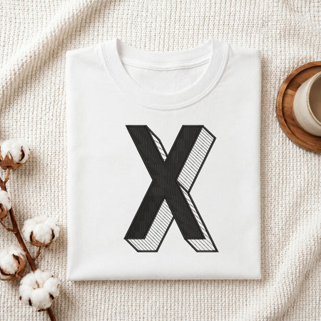 A neatly folded white crewneck t-shirt featuring a stitched 3D block letter "X" design, styled with cotton branches and a wooden coaster.