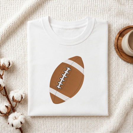 Folded white cotton t-shirt mockup featuring a football machine embroidery design, styled with cotton stems and a wooden cup