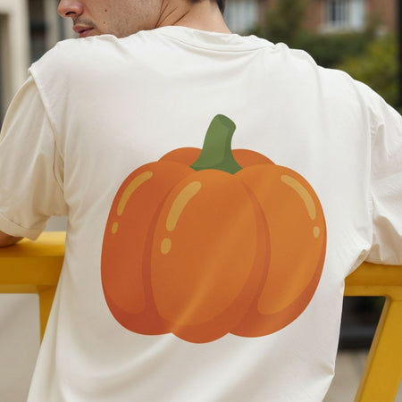 A man viewed from behind wearing a white t-shirt with a large orange pumpkin graphic printed on the back, sitting on a yellow bench.