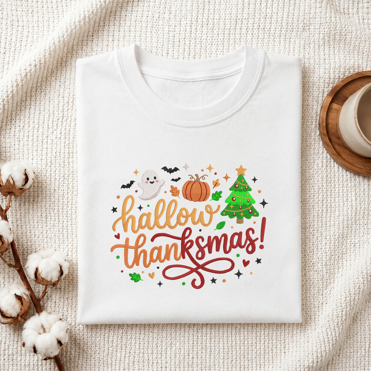 Folded white cotton t-shirt mockup featuring a "Hallowthanksmas!" holiday mashup machine embroidery design, styled with cotton stems and a wooden cup   