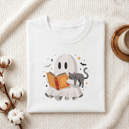 Woman carrying a white natural canvas tote bag featuring an embroidered cute ghost reading with a cat design in a bright, modern interior setting.