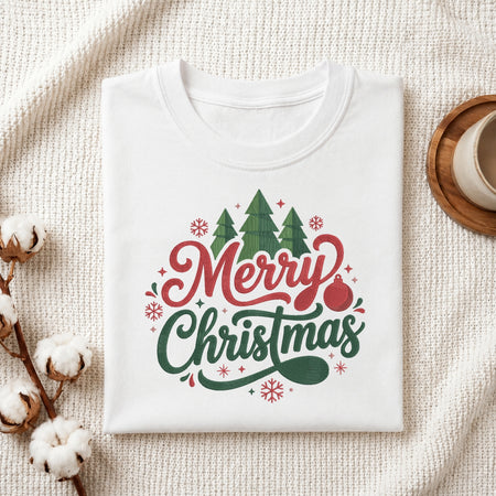 A folded white crewneck t-shirt with a 'Merry Christmas' graphic print, styled on a textured cream knit blanket with cotton bolls and a coffee cup in the background.