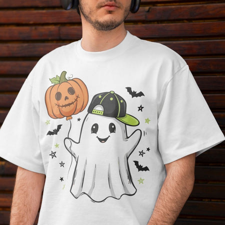 A man wearing a white graphic t-shirt with a cartoon ghost, pumpkin, and bats design, set against a dark wooden background.